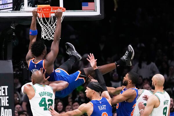 New York Knicks forward OG Anunoby, top, hangs from the rim after dunking against the Boston Celtics during the second half of Game 1 of an NBA basketball second-round playoff series Monday, May 5, 2025, in Boston. (AP Photo/Charles Krupa)