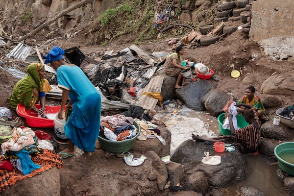 Women wash clothes in a stream in the Kaweni slum on the outskirts of Mamoudzou in the French Indian Ocean island of Mayotte, Thursday, Dec. 19, 2024, after Cyclone Chido. (AP Photo/Adrienne Surprenant)