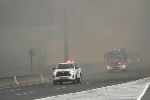 Israeli fire department crews drives through smoke from a burning fire on the freeway near Jerusalem, Wednesday, April 30, 2025. (AP Photo/Mahmoud Illean)