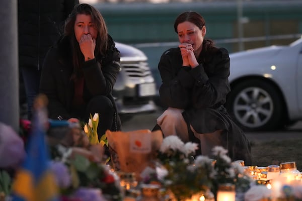 Two women stand by candles and flowers during a vigil near the scene of a shooting at an adult education center on the outskirts of Orebro, Sweden, Thursday, Feb. 6, 2025. (AP Photo/Sergei Grits)