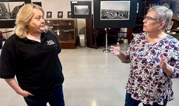 Jackson County Historical Society President Laura Cates Duncan, right, and Mary Riseling, a society board member and coordinator of the 100th anniversary commemoration of the Tri-State Tornado, discuss the March 18, 1925 cataclysm while standing among a gallery of photos on display at the society's office on March 11, 2025 in Murphysboro, Ill. (AP Photo/John O'Connor)