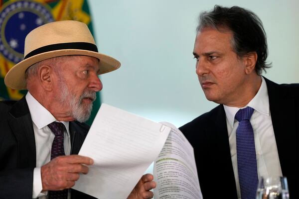 Brazil's President Luiz Inacio Lula da Silva, left, speaks with Education Minister Camilo Santana, about a bill that restricts the use of cell phones in schools nationwide, during a ceremony at the Planalto Palace, in Brasilia, Brazil, Monday, Jan. 13, 2025. (AP Photo/Eraldo Peres)