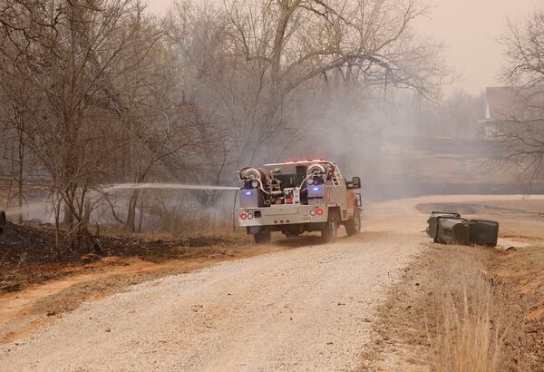 Norman Oklahoma fire crews put out hot spots following a wildfire SE of Norman on Friday, March 14, 2025. (AP Photo/Alonzo Adams)