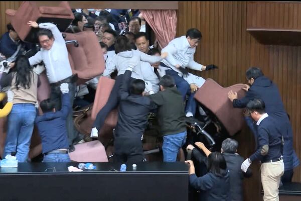 In this image made from video by Taiwan's EBC, lawmakers from the Democratic Progressive Party use chairs to block the entrance as members of the Nationalist Party, or Kuomintang, try to break into the Legislature in Taipei, Taiwan on Friday, Dec. 20, 2024. (EBC via AP )