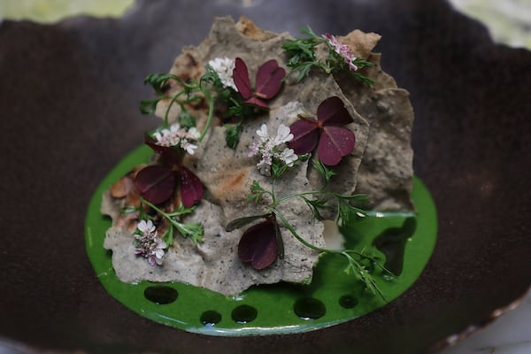 A moro crab dish in sunflower seed green pipián, Thai lime and basil with blue corn tostadas and flowers sits on display at the Quintonil restaurant in Mexico City, Friday, Feb. 28, 2025. (AP Photo/Ginnette Riquelme)