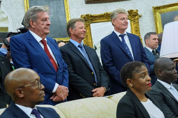 South African businessman Johann Rupert, left, and former golfer from South Africa Ernie Els, right, look on as President Donald Trump meets South African President Cyril Ramaphosa in the Oval Office of the White House, Wednesday, May 21, 2025, in Washington. (AP Photo/Evan Vucci)