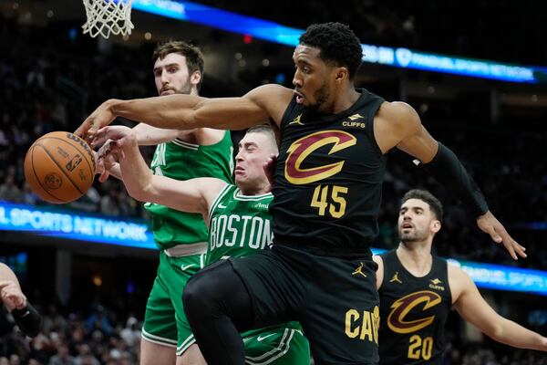 Boston Celtics center Luke Kornet, left, guard Payton Pritchard, center, and Cleveland Cavaliers guard Donovan Mitchell (45) reach for a rebound in the second half of an NBA basketball game, Tuesday, Feb. 4, 2025, in Cleveland. (AP Photo/Sue Ogrocki)