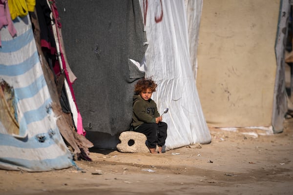 A child sits outside a tent at a camp for displaced Palestinians in Deir al-Balah, central Gaza Strip, Friday Jan. 17, 2025. (AP Photo/Abdel Kareem Hana)