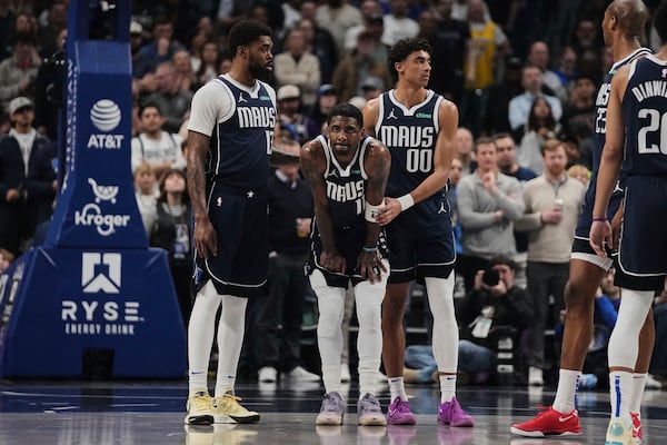 Dallas Mavericks' Naji Marshall, left, and Max Christie (00) stand by Kyrie Irving (11), center, after Irving shot free throws after suffering an injury in the first half of an NBA basketball game against the Sacramento Kings in Dallas, Monday, March 3, 2025. (AP Photo/Tony Gutierrez)