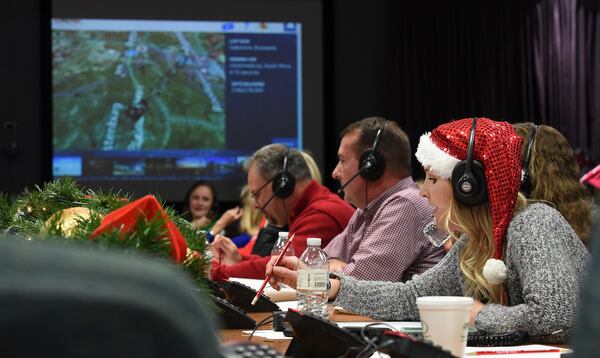 FILE - Santa tracker volunteer Meghan Huyck, right, and other volunteers answer phone calls from children all over the world at Peterson Air Force Base in Colorado Springs, Colo., Dec. 24, 2017. (Jerilee Bennett/The Gazette via AP, File)