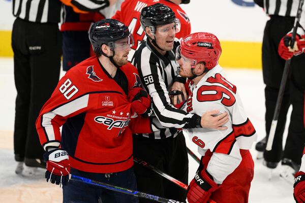 Washington Capitals left wing Pierre-Luc Dubois (80) and Carolina Hurricanes center Jack Roslovic (96) are separated by linesman Ryan Gibbons (58) in the third period of Game 2 of a second-round NHL hockey playoff series Thursday, May 8, 2025, in Washington. (AP Photo/Nick Wass)