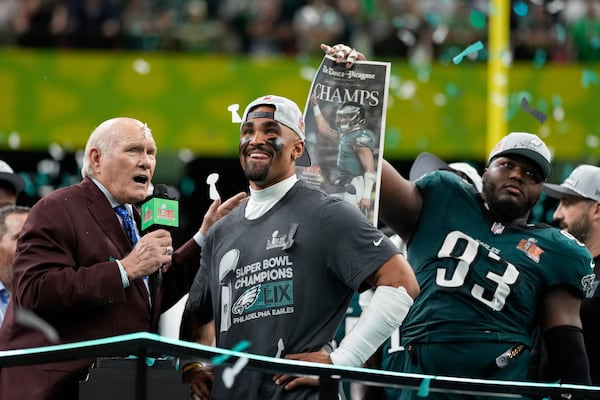 Philadelphia Eagles quarterback Jalen Hurts smiles on the podium with Terry Bradshaw and defensive tackle Milton Williams (93) after a win over the Kansas City Chiefs during the NFL Super Bowl 59 football game, Sunday, Feb. 9, 2025, in New Orleans. (AP Photo/Matt Slocum)