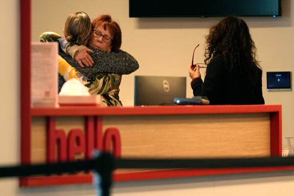 Women embrace in the reception area of The Skating Club of Boston, where six athletes, coaches and family associated with the club are believed to have perished in the collision of a passenger aircraft and military helicopter in Washington, Thursday, Jan. 30, 2025, in Norwood, Mass. (AP Photo/Robert F. Bukaty)