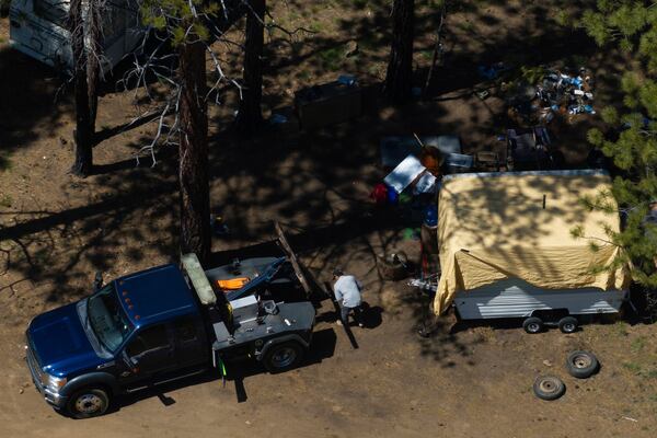 A tow truck driver helps removing a trailer for a person staying at a homeless encampment in Deschutes National Forest, Thursday, May 1, 2025, near Bend, Ore. (AP Photo/Jenny Kane)