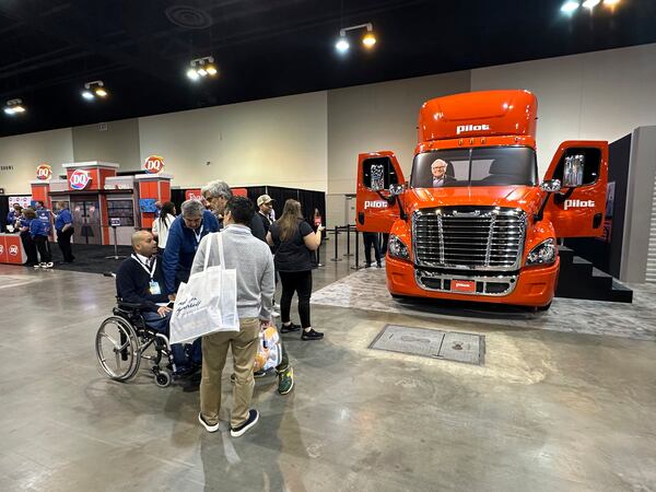 Berkshire Hathaway shareholders check out the booth for the company's Pilot truck stop chain with a photo of Warren Buffett riding in the truck on Friday, May 2, 2025 in Omaha, Neb. (AP Photo/Josh Funk)