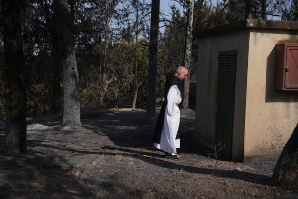 A Roman Catholic Trappist monk treads the scorched ground as Israeli fire crews battle a nearby wildfire in Latrun, Israel, outside of Jerusalem, Thursday, May 1, 2025. (AP Photo/Ohad Zwigenberg)