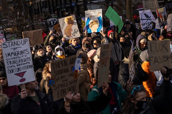 Demonstrators raise signs during a protest outside City Hall, Wednesday, Feb. 5, 2025, in New York. (AP Photo/Yuki Iwamura)