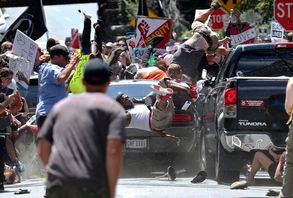 FILE - People fly into the air as a vehicle drives into a group of protesters demonstrating against a white nationalist rally in Charlottesville, Va., Saturday, Aug. 12, 2017. (Ryan M. Kelly/The Daily Progress via AP, File)