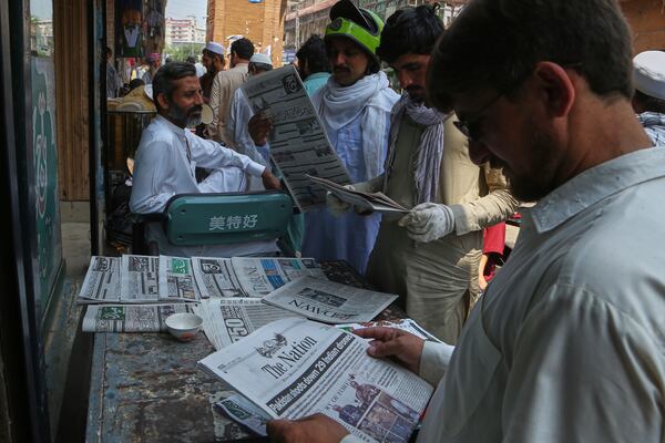 People read morning newspapers covering front page story about Pakistan and India military tension, at a stall in Peshawar, Pakistan, Friday, May 9, 2025. (AP Photo/Muhammad Sajjad)