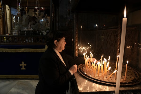 A worshipper lights a candle in the Church of the Nativity, where Christians believe Jesus Christ was born, ahead of Christmas in the West Bank city of Bethlehem, Tuesday, Dec. 17, 2024. (AP Photo/Mahmoud Illean)