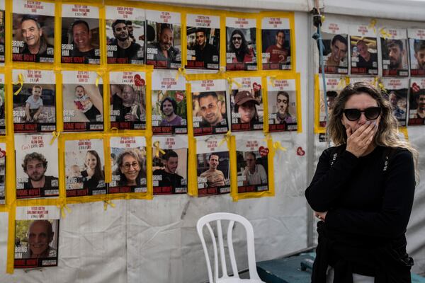 A woman reacts as she stands next to photos of hostages held in the Gaza Strip by Hamas, displayed on a tent at a plaza known as the Hostages Square in Tel Aviv, Israel, on Wednesday, Feb. 19, 2025. (AP Photo/Oded Balilty)