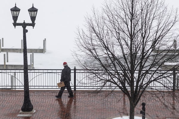 A person walks down the sidewalk as a snowstorm rolls in, Wednesday, Feb. 12, 2025 in Uptown Bay City, Mich. (Kaytie Boomer/The Bay City Times via AP)