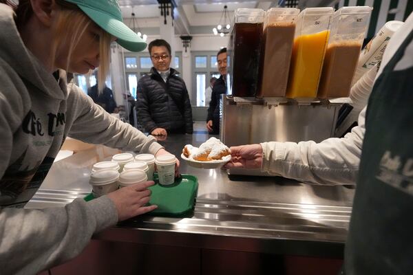 Patrons are served beignets and cafe au lait in Cafe du Monde in City Park in New Orleans, Friday, Jan. 24, 2025. (AP Photo/Gerald Herbert)