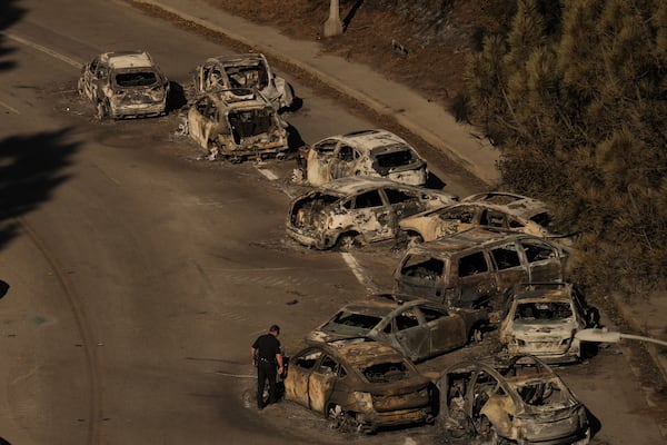 Police officers inspect cars abandoned on Sunset Boulevard during by the Palisades Fire in Palisades, Calif., Wednesday, Jan. 15, 2025. (AP Photo/Jae C. Hong)