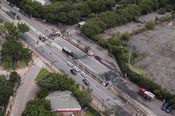 The crash site of a small plane, right, that burned a bus, left, covers an avenue in Sao Paulo, Friday, Feb. 7, 2025. (AP Photo/Ettore Chiereguini)