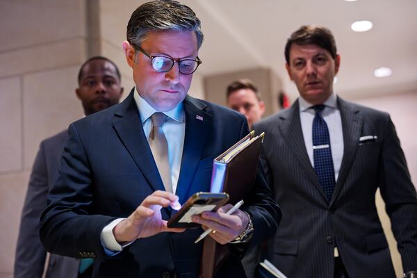 Speaker of the House Mike Johnson, R-La., checks his phone as he arrives to meet with reporters as Republicans push ahead with a go-it-alone strategy on an interim spending bill that would keep federal agencies funded through Sept. 30, at the Capitol, in Washington, Tuesday, March 11, 2025. (AP Photo/J. Scott Applewhite)