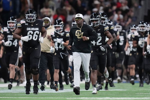 Colorado head coach Deion Sanders, center, takes the field with his team before the Alamo Bowl NCAA college football game against BYU, Saturday, Dec. 28, 2024, in San Antonio. (AP Photo/Eric Gay)