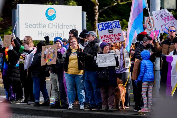 FILE - People wave signs to passing cars during a pro-transgender rights protest outside of Seattle Children's Hospital after the institution postponed some gender-affirming surgeries for minors following an executive order by President Donald Trump, Sunday, Feb. 9, 2025, in Seattle. (AP Photo/Lindsey Wasson, File)