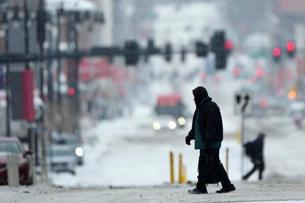 Pedestrians cross a snowy street in downtown Kansas City, Mo., as a winter storm passed through the area Wednesday, Feb. 12, 2025. (AP Photo/Charlie Riedel)