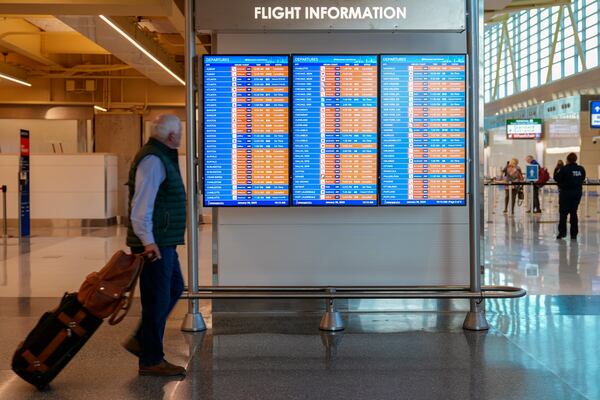 A passenger walks past a flight information board displaying several canceled flights at Ronald Reagan Washington National Airport, Thursday, Jan. 30, 2025, in Arlington, Va. (AP Photo/Stephanie Scarbrough)