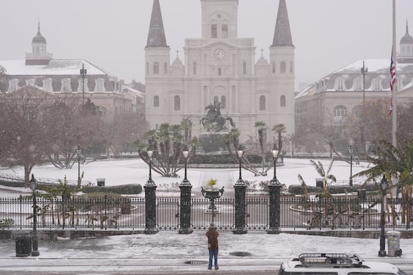 A person stops to take a picture at Jackson Square as snow falls in the French Quarter in New Orleans, Tuesday, Jan. 21, 2025. (AP Photo/Gerald Herbert)