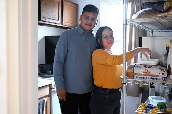 In this Jan. 3, 2025 photo, Rogers Lopez stands with his wife Karina Canizarez, right, in the kitchen of their apartment in New Milford, Conn. (AP Photo/Jessica Hill)