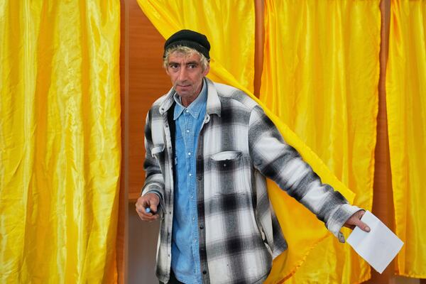 A man exits a voting cabin before casting his vote in the first round of the presidential election redo in Mogosoaia, Romania, Sunday, May 4, 2025. (AP Photo/Vadim Ghirda)