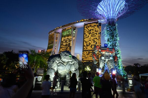 FILE - Tourists take pictures in front of two majestic life-size statues of Optimus Prime and Optimus Primal at Gardens By The Bay in Singapore, on March 18, 2023. (AP Photo/Yeen Ling Chong, File)