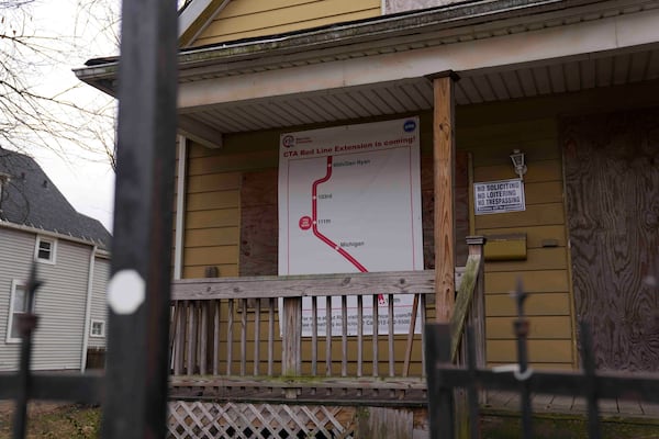 A sign reads "CTA Red Line Extension is coming!" on a boarded-up property set for demolition to make room for a new train station where the Chicago Transit Authority plans to expand the Red Line train route on West 111th Street, Wednesday, Dec. 11, 2024, in the Roseland neighborhood of Chicago. (AP Photo/Erin Hooley)