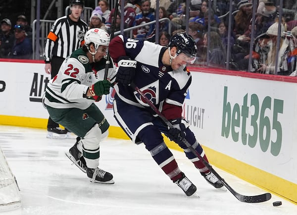 Colorado Avalanche right wing Mikko Rantanen, right, collects the puck as Minnesota Wild center Marat Khusnutdinov defends in the third period of an NHL hockey game Monday, Jan. 20, 2025, in Denver. (AP Photo/David Zalubowski)