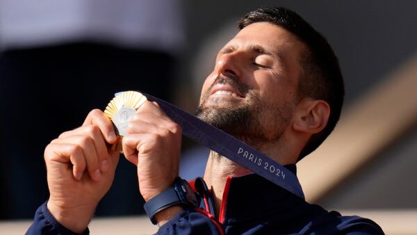 FILE - Serbia's Novak Djokovic watches his gold medal after defeating Spain's Carlos Alcaraz in the men's singles tennis final at the Roland Garros stadium during the 2024 Summer Olympics, Sunday, Aug. 4, 2024, in Paris, France. (AP Photo/Manu Fernandez, File)