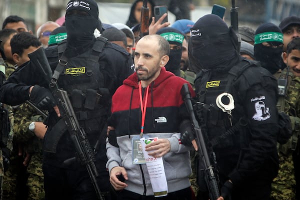 Israeli hostage Tal Shoham is escorted by Hamas fighters before being handed over to the Red Cross in Rafah, southern Gaza Strip, on Saturday, Feb. 22, 2025. (AP Photo/Jehad Alshrafi)