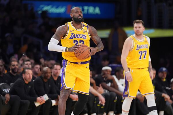 Los Angeles Lakers forward LeBron James, left, passes as teammate guard Luka Doncic looks on during the first half of an NBA basketball game against the Utah Jazz, Monday, Feb. 10, 2025, in Los Angeles. (AP Photo/Mark J. Terrill)