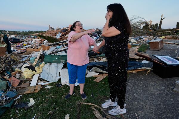 Bea Johnson, left, reaches for her sister Kristie Sexton, right, as she reacts standing next to her destroyed home after a severe storm passed through the area, Saturday, May 17, 2025, in London, Ky. (AP Photo/Carolyn Kaster)