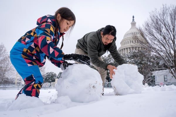 Johnny Hong, of Washington, and his daughter Eliyah Hong, 5, build a snowman by the Capitol, Wednesday, Feb. 12, 2025, after a snowstorm in Washington. (AP Photo/Jacquelyn Martin)