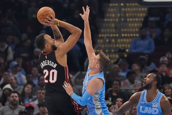 Miami Heat forward Kyle Anderson (20) shoots as Cleveland Cavaliers guard Sam Merrill, center, defends in the first half of an NBA basketball game Wednesday, March 5, 2025, in Cleveland. (AP Photo/Sue Ogrocki)