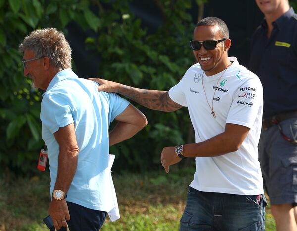 FILE - Mercedes driver Lewis Hamilton, right, of Britain shares a light moment with Eddie Jordan, owner of Jordan Grand Prix, which raced in Formula One from 1991 to 2005, as he arrives for the first practice session for the Singapore F1 Grand Prix on the Marina Bay City Circuit in Singapore, Friday, Sept. 20, 2013. (AP Photo/Dita Alangkara, File)