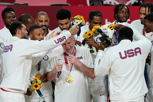 FILE - United States players put a gold medal on head coach Gregg Popovich during the men's basketball medal ceremony at the 2020 Summer Olympics, Saturday, Aug. 7, 2021, in Tokyo, Japan. (AP Photo/Charlie Neibergall, File)