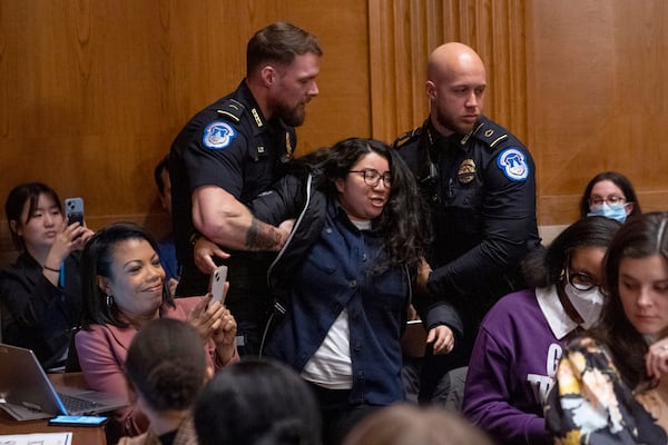 A protester is removed while calling out for protections for transgender and immigrant students, during a nomination hearing for Linda McMahon, President Donald Trump's nominee for Secretary of Education, at a Health, Education, and Labor Committee hearing, Thursday, Feb. 13, 2025, in Washington. (AP Photo/Jacquelyn Martin)