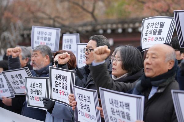 Members of civic groups shout slogans during a news conference demanding the arrest of President Yoon Suk Yeol near the presidential residence in Seoul, South Korea, Tuesday, Dec. 17, 2024. The letters read "Immediately arrest Yoon Suk Yeol." (AP Photo/Lee Jin-man)